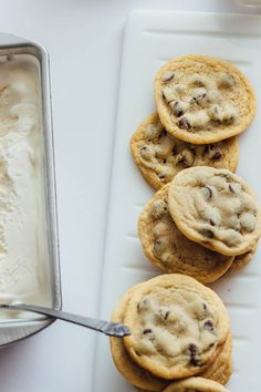 chocolate chip cookies and ice cream are on a white tray next to a cookie tin