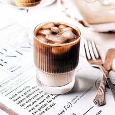 an iced drink with ice cubes in it on top of a table next to silverware