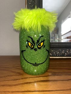 a green grin face jar sitting on top of a wooden table