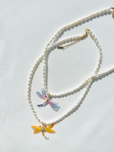 two necklaces with dragon charms hanging from them on a white tablecloth covered surface