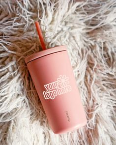 a pink tumbler cup sitting on top of a fluffy white blanket