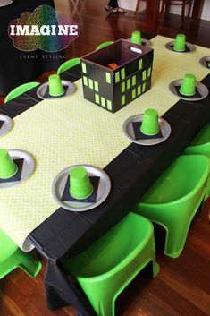 a table set up with green chairs and black table cloths for a minecraft birthday party