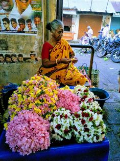 a woman sitting in front of a bunch of flowers