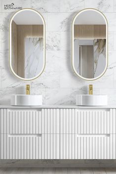 two sinks and mirrors in a bathroom with white marble walls, gold trimmings