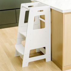 a white step stool sitting next to a kitchen counter top on a hard wood floor