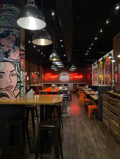 the interior of a restaurant with wooden tables and stools in front of large murals