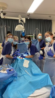 four women in scrubs and masks are preparing to perform surgery on an operating table