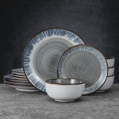 a set of four dinner plates with blue and white designs on the rims, in front of a dark background