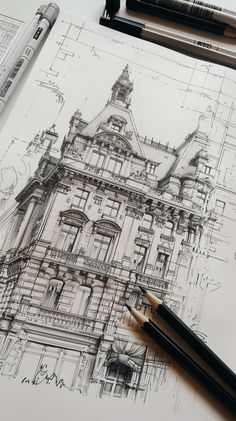 a drawing of a large building on top of a table next to some pencils