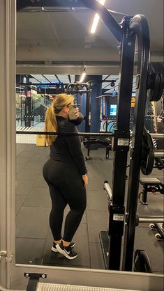 a woman is taking a selfie in the mirror while standing next to a gym machine