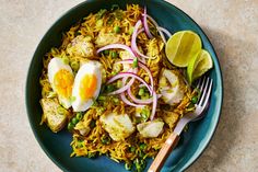 a blue plate topped with rice and fried eggs next to a fork on a table