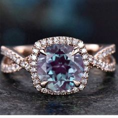 an engagement ring with a large blue stone surrounded by white and rose gold diamonds, on top of a black surface