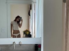 a woman taking a selfie in front of a bathroom mirror