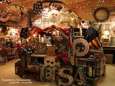 an assortment of patriotic items on display in a room with lights strung from the ceiling