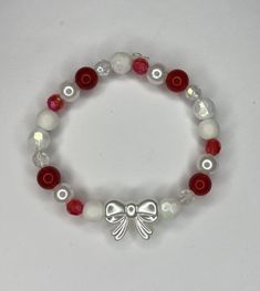 A red and white bow bracelet Red Aesthetic Bracelet, Christmas Jewelry Aesthetic, Cheap Beaded Bracelets For Christmas, Adjustable Bow Bracelet Gift, Adjustable Bow Bracelet For Gift, Adjustable Bow Bracelet As Gift, White Jewelry With Bow For Gifts, White Adjustable Beaded Bracelets For Holidays, Adjustable White Beaded Bracelets For Holiday