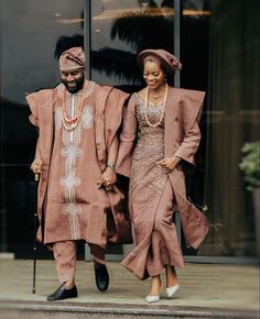 an african couple dressed in traditional clothing walking down the street