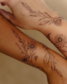 two people with tattoos on their arms holding each other's hands, one has a flower and the other has leaves