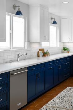 a large kitchen with blue cabinets and white counter tops, along with a rug on the floor