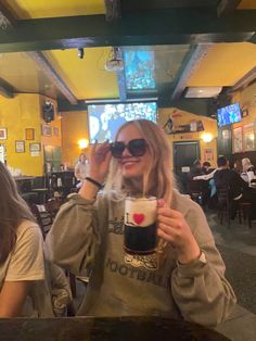 two women sitting at a table with drinks in front of them and one woman holding up her glasses