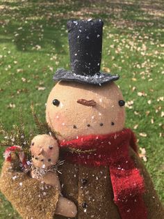 a snowman with a baby in his arms is standing on the grass and it's snowing