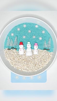 three snowmen in a bowl with trees and snow flakes on the ground behind them