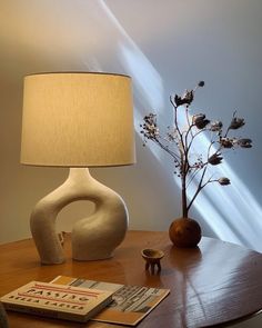 a table with a lamp, vase and book on it