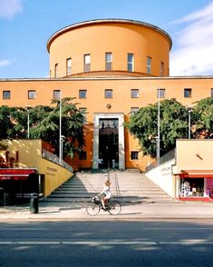 a person riding a bike in front of a building with steps leading up to it