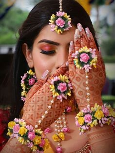 a woman with her hands on her face and flowers in her hair, covering her eyes