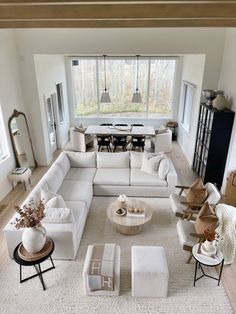 a living room filled with white furniture and lots of windows above the couches in front of them