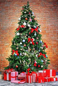 a christmas tree with presents under it in front of a brick wall and red bricks