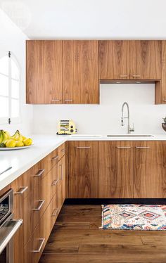 a kitchen with wooden cabinets and white counter tops, along with a rug on the floor