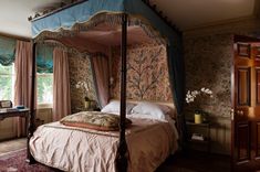 a canopy bed in a bedroom with floral wallpaper