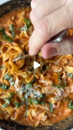 a person is spooning some food out of a pan with pasta and spinach