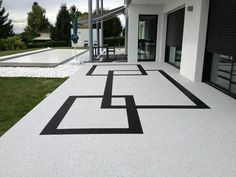 an outdoor walkway with black and white designs on the concrete, leading to a building