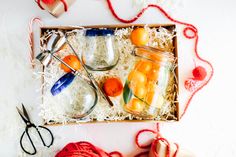 a box with some jars and scissors on top of it next to yarn, twine and other items