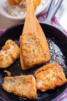 some food is cooking in a skillet with a wooden spoon and rice on the side