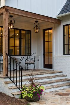 a porch with steps leading up to the front door and patio area on either side