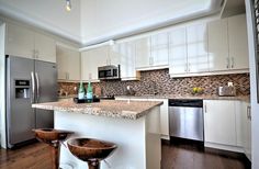 a kitchen with stainless steel appliances and white cabinetry is pictured in this image, there are two stools on the counter