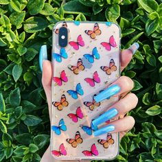 a woman's hand holding an iphone case with blue nail polish and butterflies on it