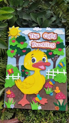 the ugly duckling book is sitting in front of some plants and trees, with an image of a rubber duck on it's cover