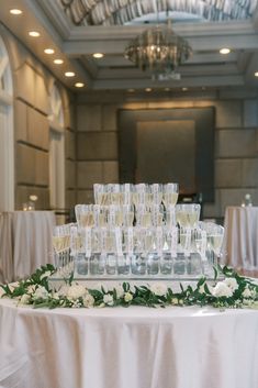 a table topped with lots of glasses filled with champagne and flowers on top of it