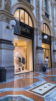 two people are walking in front of a dior store