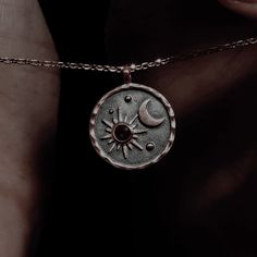 a person wearing a necklace with the sun and moon on it