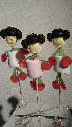 three cake toppers made to look like people holding marshmallows and cherries