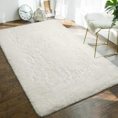 a large white rug in the corner of a room with a chair and clock on the wall