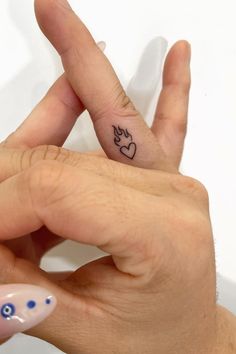 a woman's hand with a small tattoo on her left thumb and an eyeball in the middle