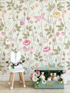 a floral wallpaper with pink flowers and green leaves on the wall next to a white chair