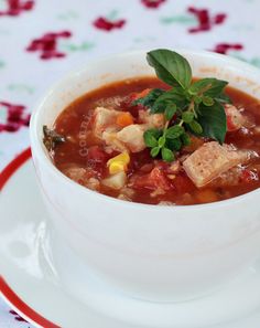 a white bowl filled with soup on top of a red and white plate