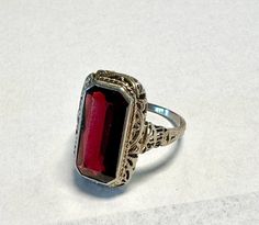 14k Garnet ring, white gold filigree, stamped 14k, Gorgeous bezel set rectangular genuine red Garnet.  Condition is very good for its age any wear commensurate with age, pictures show the details.  Size 6 1/4, 3/4" north to south on finger, Garnet 15mm by 7mm, wt.- 3.7 grams. Edwardian or early Deco,  Elegant easy to wear design. Garnet Ring, Gold Filigree, Garnet Rings, Red Garnet, Early 1900s, Bezel Setting, Deep Red, Rings Statement, Halloween Shopping