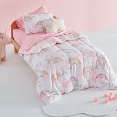 a child's bed with pink sheets and unicorns on the comforter, next to a toy horse